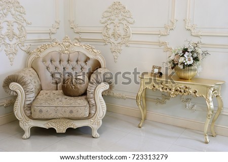 Empty baroque studio with armchair and small gilt table and molding on walls