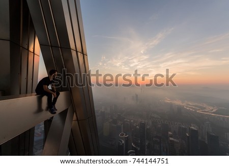 Man sits on rooftop and looks at morning cityscape, Shenzhen, China