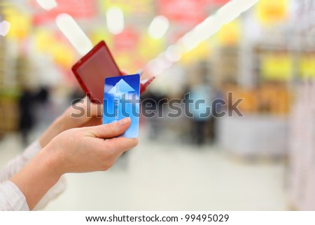 Woman gets credit card from purse in store; shallow depth of field