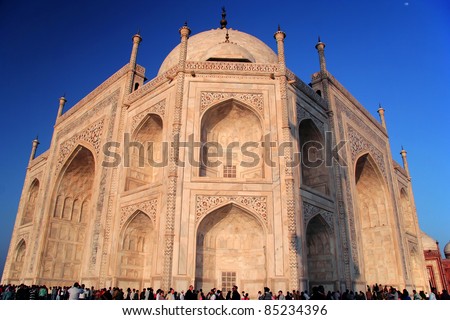 Unusual perspective of Taj Mahal at Agra, India drenched by the setting sun. It\'s amazing to see the scale of this magnificent structure compared to people. Also visible are some intricate artwork.