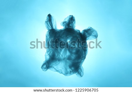 Pollution of the environment of the planet plastic. Blue plastic bag in the shape of turtle in the world ocean.