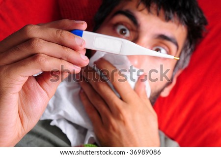 A sick man with a fever, checking his temperature with an electric thermometer. His mouth is covered by a tissue paper and his eyes are big and shocked at the temperature on the thermometer.