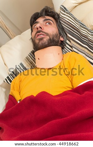 A bearded man laying back, wearing a neck brace.