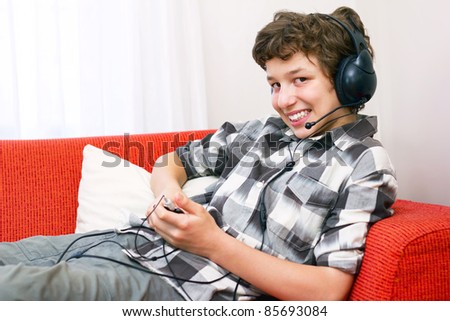 stock photo A preteen boy lays back on an orange couch with big headphones