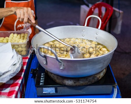 Asia woman wearing apron, fried flour in hot oil pan at street night market