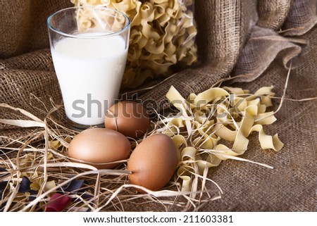 eggs, milk as pasta ingredients shot with hay decoration