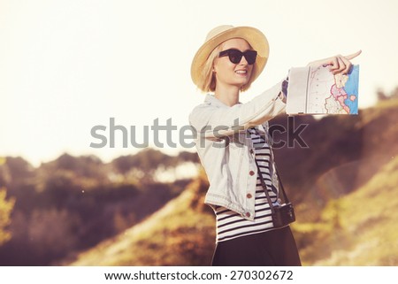 Beautiful young female tourist in nature is pointing to a direction