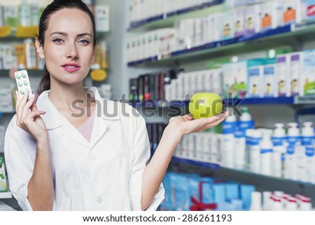 woman pharmacist is holding pills and a green apple