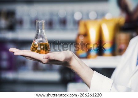 close up of a female hand, pharmacist is holding a test tube filled with chemical ingredient