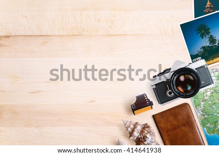 Travel and vacation concept. All photographs are taken by me. Items on aged wooden table. Vintage SLR film camera, old photos, film roll, sea shells, passport and map. Top view with copy space