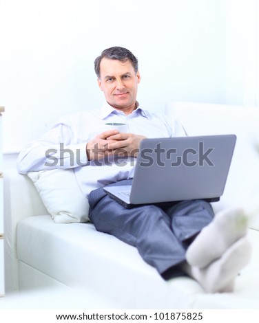 entrepreneur working from home looking very relaxed in his sofa browsing the web in his laptop computer