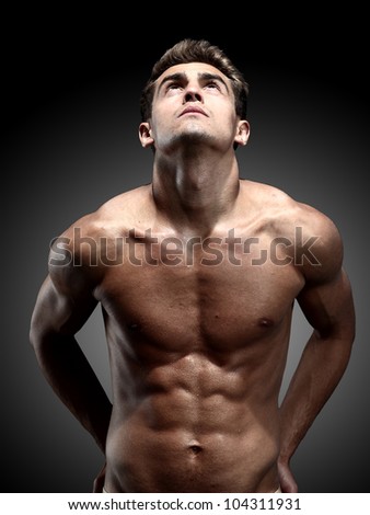 portrait of young strong man against black background