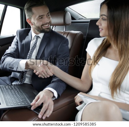 Handshake of business people in the back seat of a car