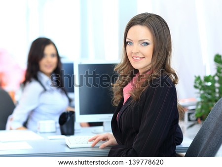 Happy young businesswoman looking behind and her colleagues working at office