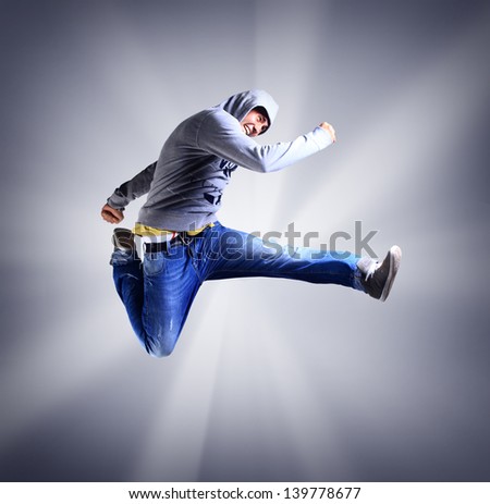 Portrait of an young man jumping in air against light background