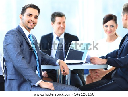 Portrait Of Mature Business Man Smiling During Meeting With Colleagues In Background