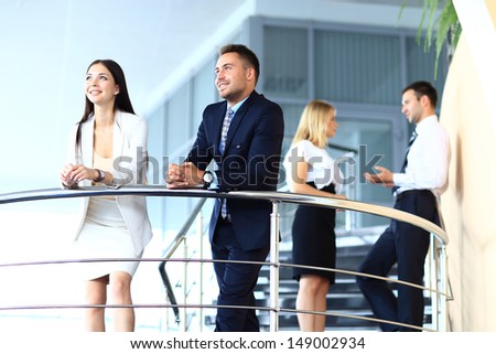 Portrait of positive business group standing on stairs of modern office