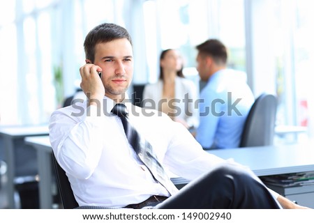 Successful Businessman Sit At His Desk While Talking On Mobile In Office