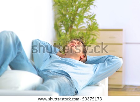 Full length of a young guy relaxing on sofa in home