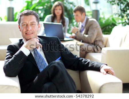 Senior business relaxed on a chair with his colleagues at a meeting in the back