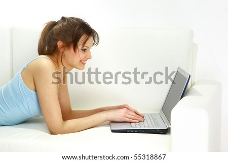 Smiling woman lying on sofa with laptop.