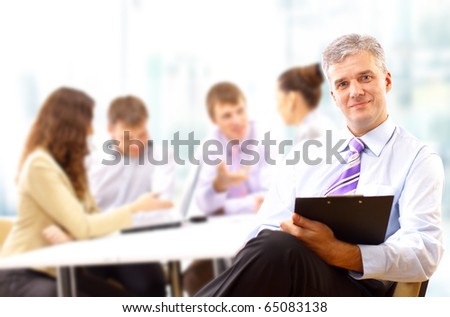 Portrait of a senior business man attending a conference with the rest of his business team