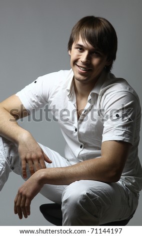 Portrait of a casual young satisfied man sitting relaxed. Isolated on white.