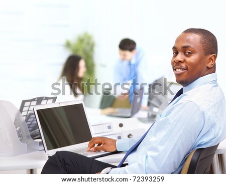 Portrait of a happy African American entrepreneur displaying computer laptop in office