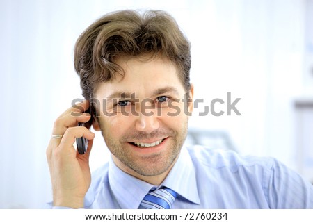 Handsome business guy working on cellphone and laptop together while at work