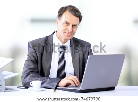 Businessman sitting at desk and working with laptop computer.
