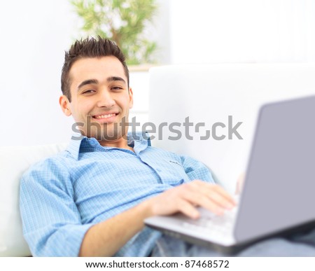Smiling young man working on laptop computer at home