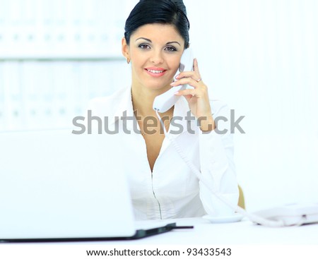 Portrait of a young woman on phone in front of a laptop computer