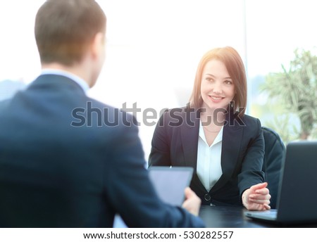 Beautiful young businesswoman conducting a job interview seated at her desk