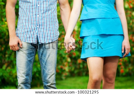 Concept shot of friendship and love of man and woman: two hands over green nature park