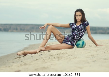 young professional gymnast woman dance with ball - outdoor sand beach