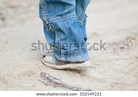 Closeup on a kids feet wearing grey sandals and jeans over ground