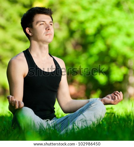 A young man doing yoga in the green park