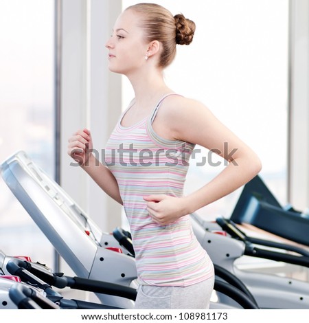 Young woman at the gym exercising. Run on a machine