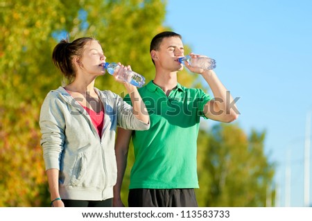 Man and woman drinking water from bottle after fitness sport exercise