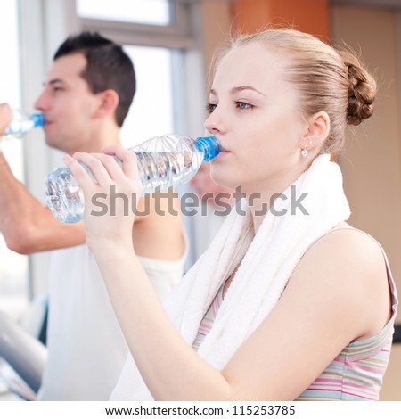 Man and woman drinking water after sports. Fitness gym.