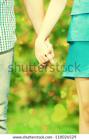 Concept shot of friendship and love of man and woman: two hands over green nature park
