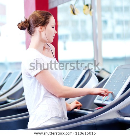 Young sporty woman run on machine in the gym centre
