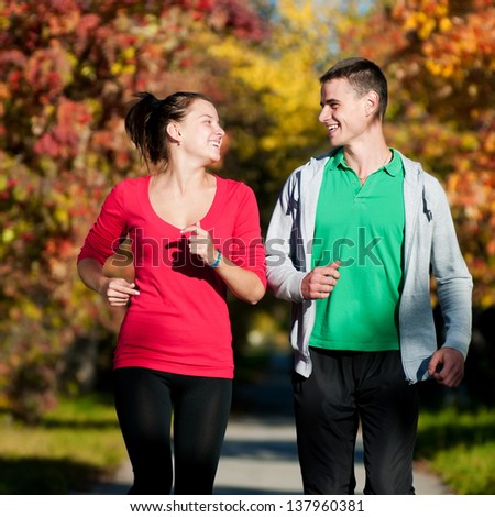 Young fitness couple of man and woman run in park