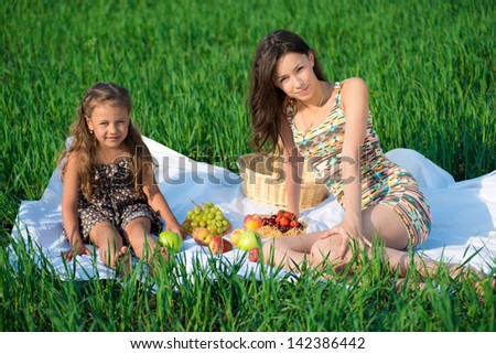 Happy girls on green grass with fruits at spring or summer park picnic