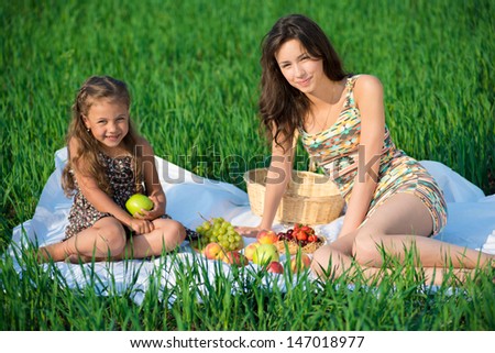 Happy girlswith fruits on green grass at spring or summer park picnic
