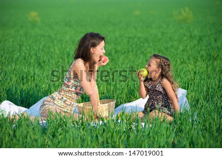 Happy girls with fruits on green grass at spring or summer park picnic