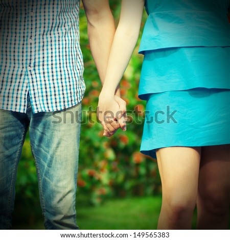 Retro style. Concept shot of friendship and love of man and woman: two hands over green nature park