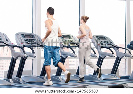 Young woman and man at the gym exercising Run on a machine Young woman and man at the gym exercising Run on a machine