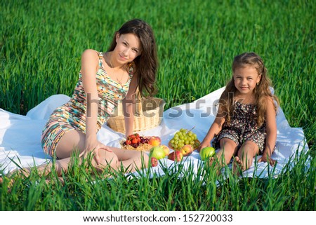 Happy girls on green grass with fruits at spring or summer park picnic