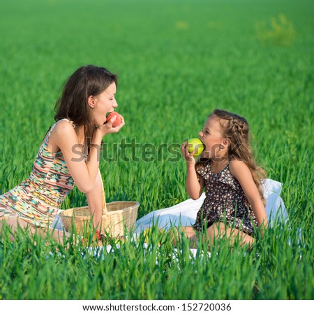 Happy girls with fruits on green grass at spring or summer park picnic